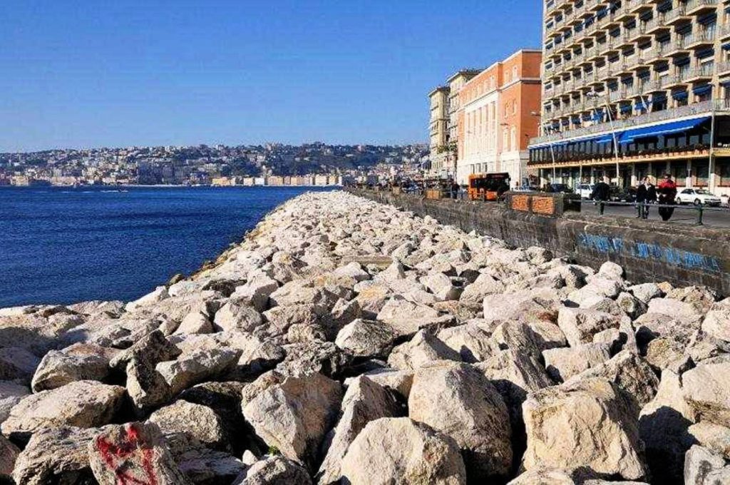 how to photograph lungomare liberato naples featuring the wide pedestrian street next to blue waves and volcanic rock barriers cleanly