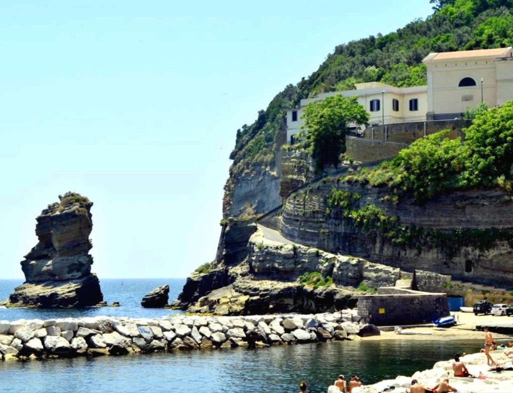 naples photography spots showing the circular volcanic islet of nisida rising calmly from the blue sea water