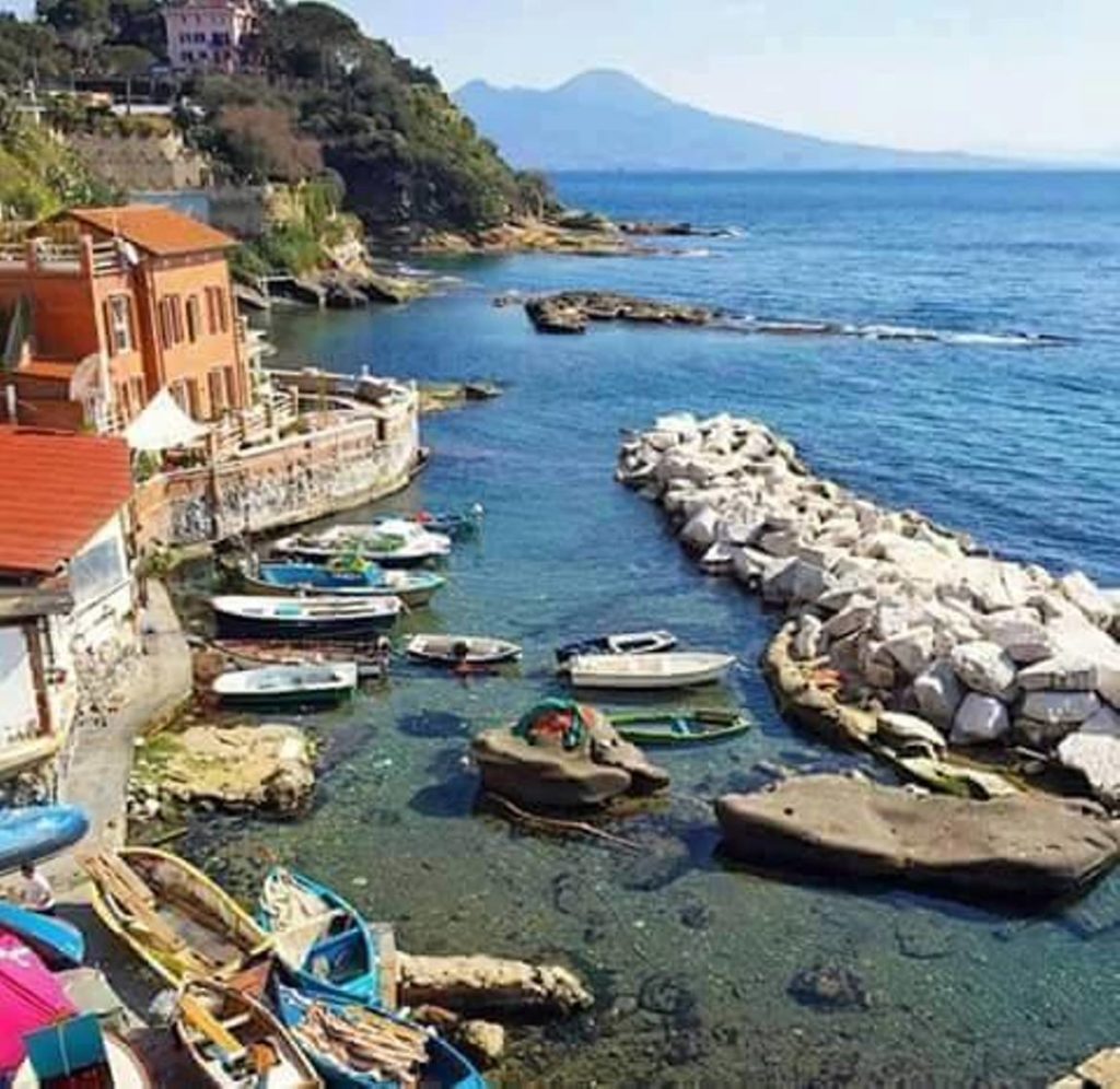naples nightlife locals enjoying fresh seafood at illuminated restaurants along the dark water of marechiaro