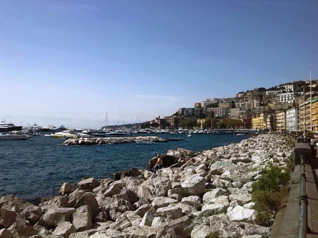 best time of day to visit seafront naples calm ocean waters reflecting the pink shades of a fresh dawn sky