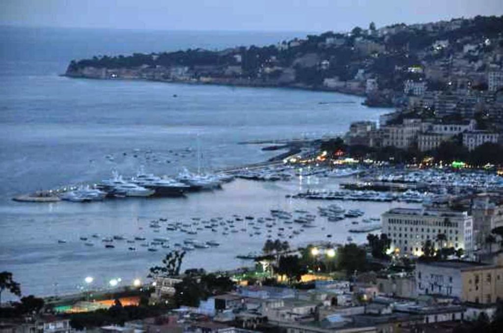 best time of day to visit porticciolo di mergellina napoli early morning sun reflecting on small wooden rowboats inside a quiet harbor