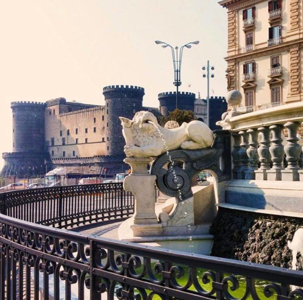 what to see near piazza municipio napoli grand stone town hall facade facing a wide white stone square with the ancient castle wall