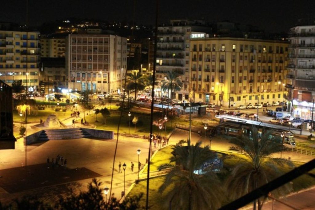 is piazza nazionale napoli safe at night wide concrete square with modern benches under tall metallic lighting poles