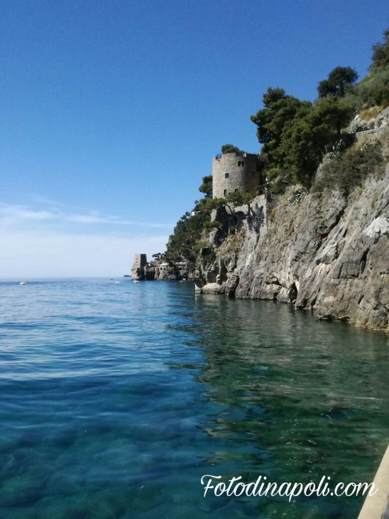 Via Positanesi d'America Positano steep narrow shaded staircase street with old irregular stone walls and distant glimpse of turquoise sea at bottom