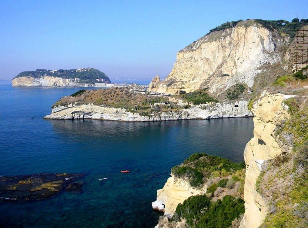 baia di trentaremi napoli photo spots showing the dramatic yellow tufa cliffs dropping into deep turquoise water cleanly