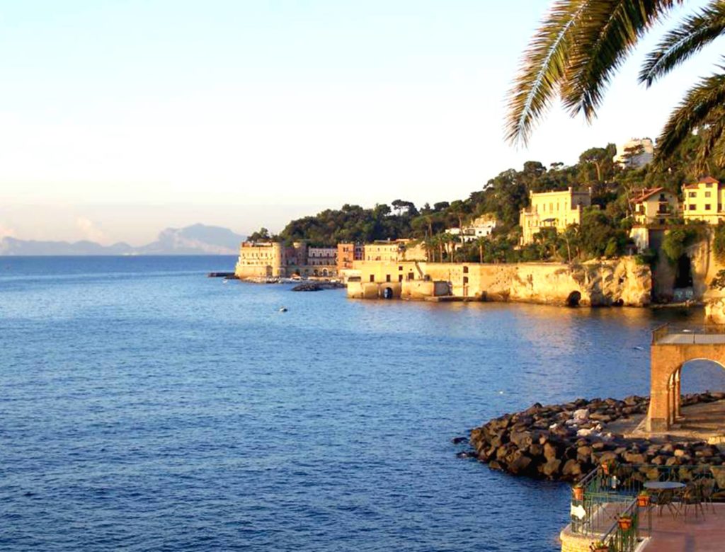best photo spots along mare posillipo napoli featuring clear blue sea waters hitting the base of ancient roman palace ruins cleanly